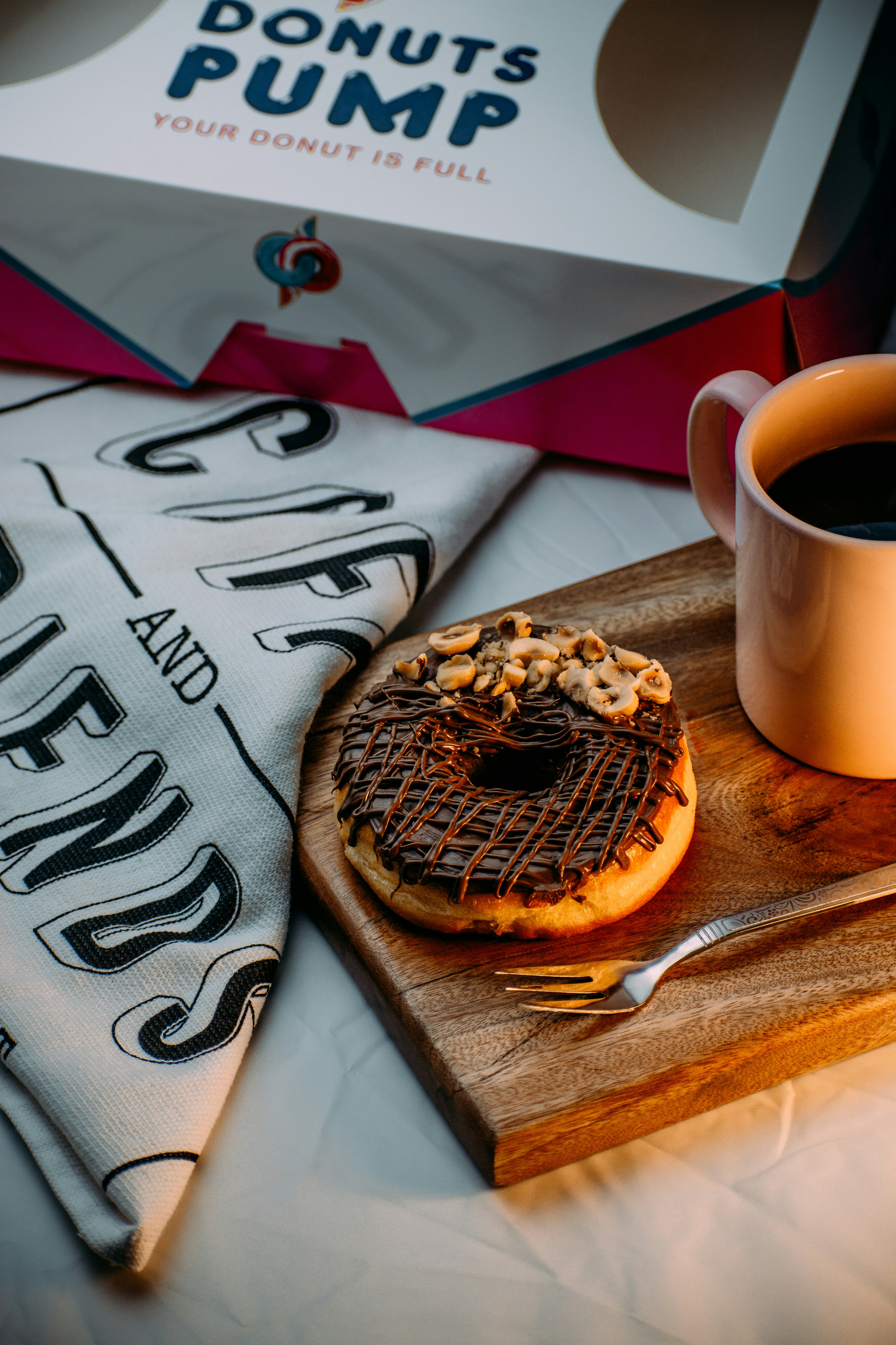 white ceramic mug beside brown pastry on brown wooden table